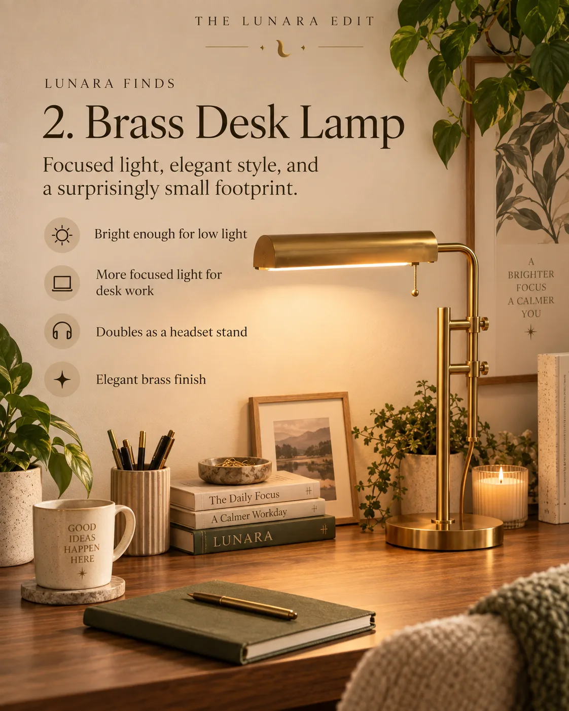 A slim brass desk lamp casting focused light over a green notebook and framed print